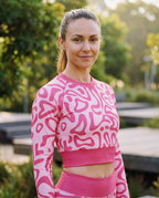 Woman wearing a pink and white patterned long-sleeve top and pants outdoors.